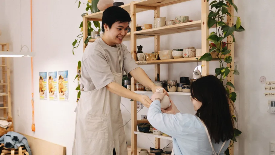 Two people exchanging pottery in a shop.