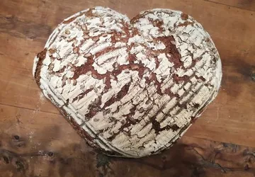 Herzförmiges Brot auf Holztisch.