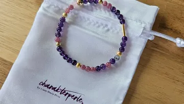 Perlenarmband auf weißem Beutel, Holzoberfläche.