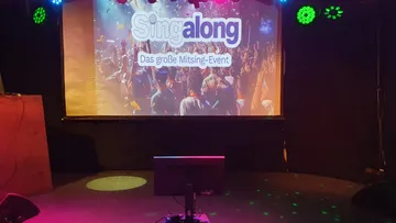 Stage with screen showing sing-along event.