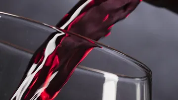 Wein ins Glas gießend, Veranstaltungsdatum angezeigt.