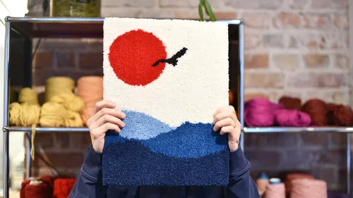 Person holding colorful textile in yarn shop.