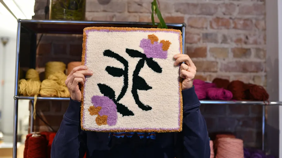 Person holding floral tapestry in yarn shop.