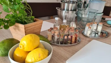 Herbs, lemons, spices, and kitchen utensils on table.