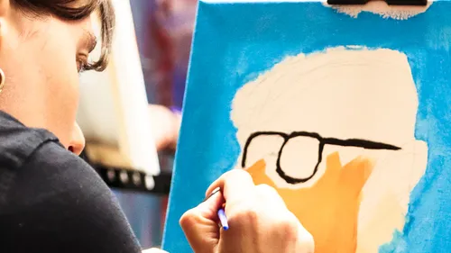 Person painting on canvas, focused indoors.