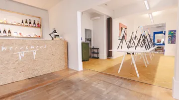 Kunstwerkstatt mit Staffeleien und Weinausstellung.