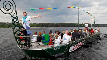 Boot mit Menschen auf See, Festflaggen oben.