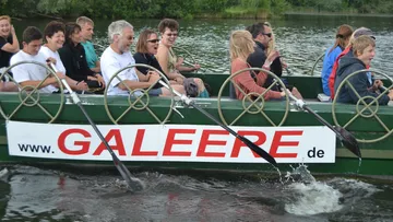 Menschen rudern ein Boot auf einem See.