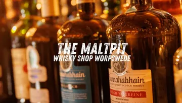Whiskyflaschen im Regal mit Laden Text.