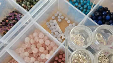 Verschiedene Perlen in Plastikbehältern organisiert.