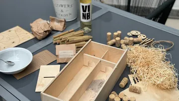 Bastelmaterialien auf Tisch, inklusive Holzkiste.
