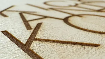 Nahaufnahme von lasergeschnittenen Buchstaben auf Holz.
