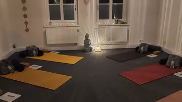 Yogamatten im Kreis angeordnet, kerzenbeleuchteter Raum.