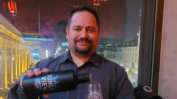 Man pouring gin into glass at night.