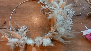 Blumenkranz mit getrockneten weißen Blumen auf Tisch.