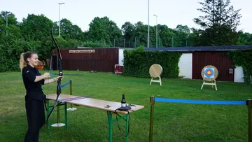 Woman practicing archery in outdoor field.