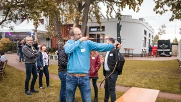 Person zielt mit Bogen bei Outdoor-Veranstaltung.