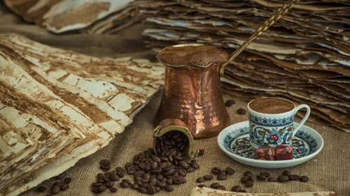Coffee cup and pot with beans, rustic background.