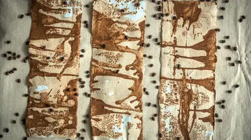 Abstract coffee-stained paper with scattered beans.