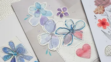 Colorful flower stickers and heart sticker on paper.