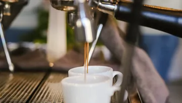 Espresso machine pouring coffee into cups.