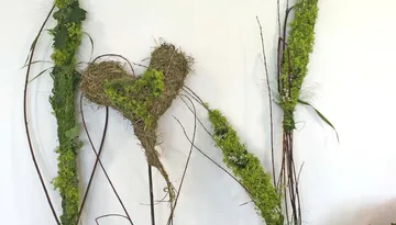 Florales Herzkunstwerk an weißer Wand.