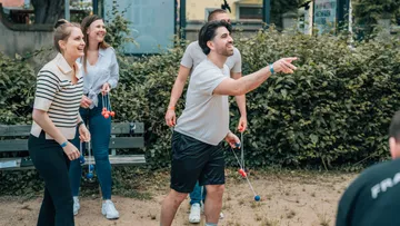 People playing outdoor game with balls, smiling.