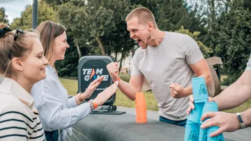 People playing cup stacking game outdoors.