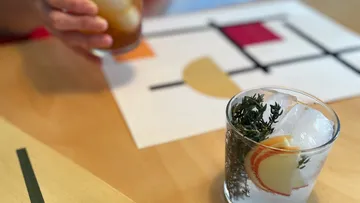 Cocktail with apple and herbs on table.