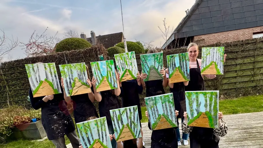 People holding paintings in outdoor garden.