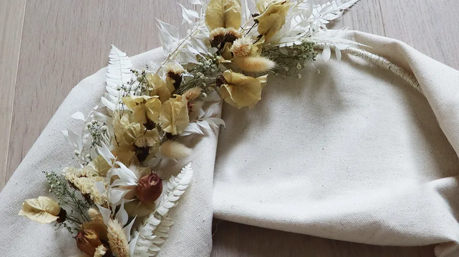 Dried flowers and bag on wooden table.