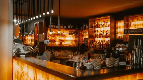 Barkeeper arbeitet hinter einer schummrig beleuchteten Bar.