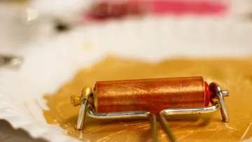 Paint roller on golden paint, close-up.