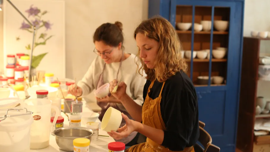 Two women painting pottery in a studio.