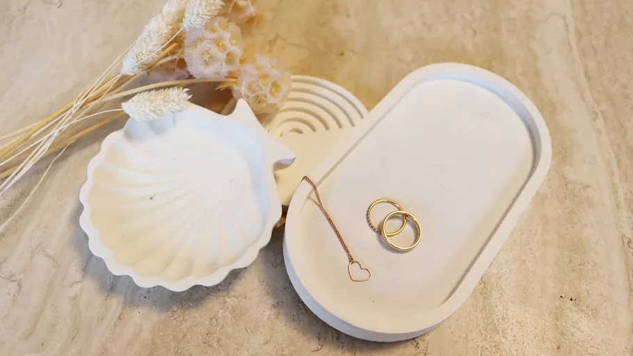 Rings on oval tray, dried flowers nearby.