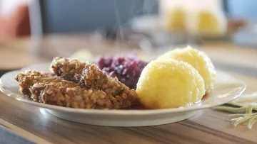 Steaming plate with meat, cabbage, dumplings.