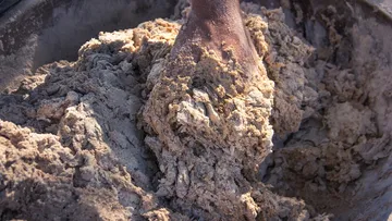 Hand mixing coarse dough in a bowl.