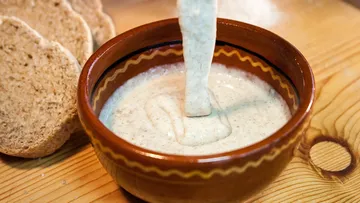 Cream being poured into a bowl, bread nearby.