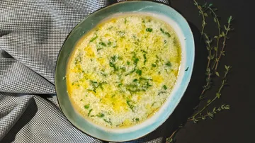 Gebackener Dip mit Käse und Kräutern auf Tisch.