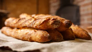 Baguettes auf Tuch in einer Bäckerei gestapelt.