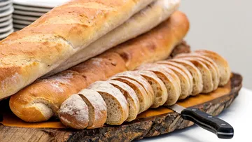 Geschnittenes Baguette und Brote auf Holzbrett.