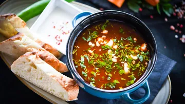 Suppe in Schüssel mit Brot auf Teller.
