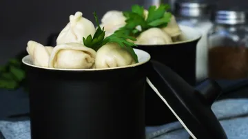 Dumplings in a pot with herbs garnish.