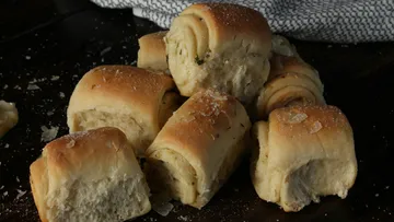Bread rolls stacked on dark surface.