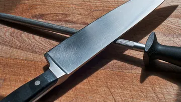 Messer und Wetzstahl auf Holzfläche.