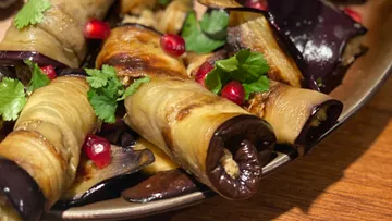 Auberginenröllchen mit Granatapfelkernen, mit Kräutern garniert.