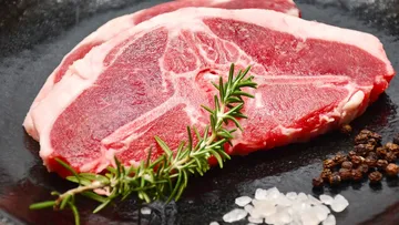 Raw steak with rosemary, salt, and pepper.