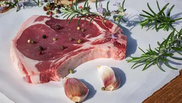 Raw meat with garlic and herbs on paper.