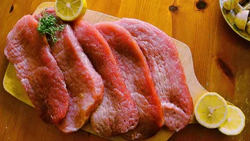 Raw beef slices on wooden board.