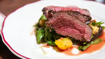 Geschnittenes Steak auf gemischten Salaten auf Teller.